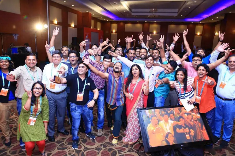 A group photo of excited participants at the conference laughing and raising their arms in the air having a good time.